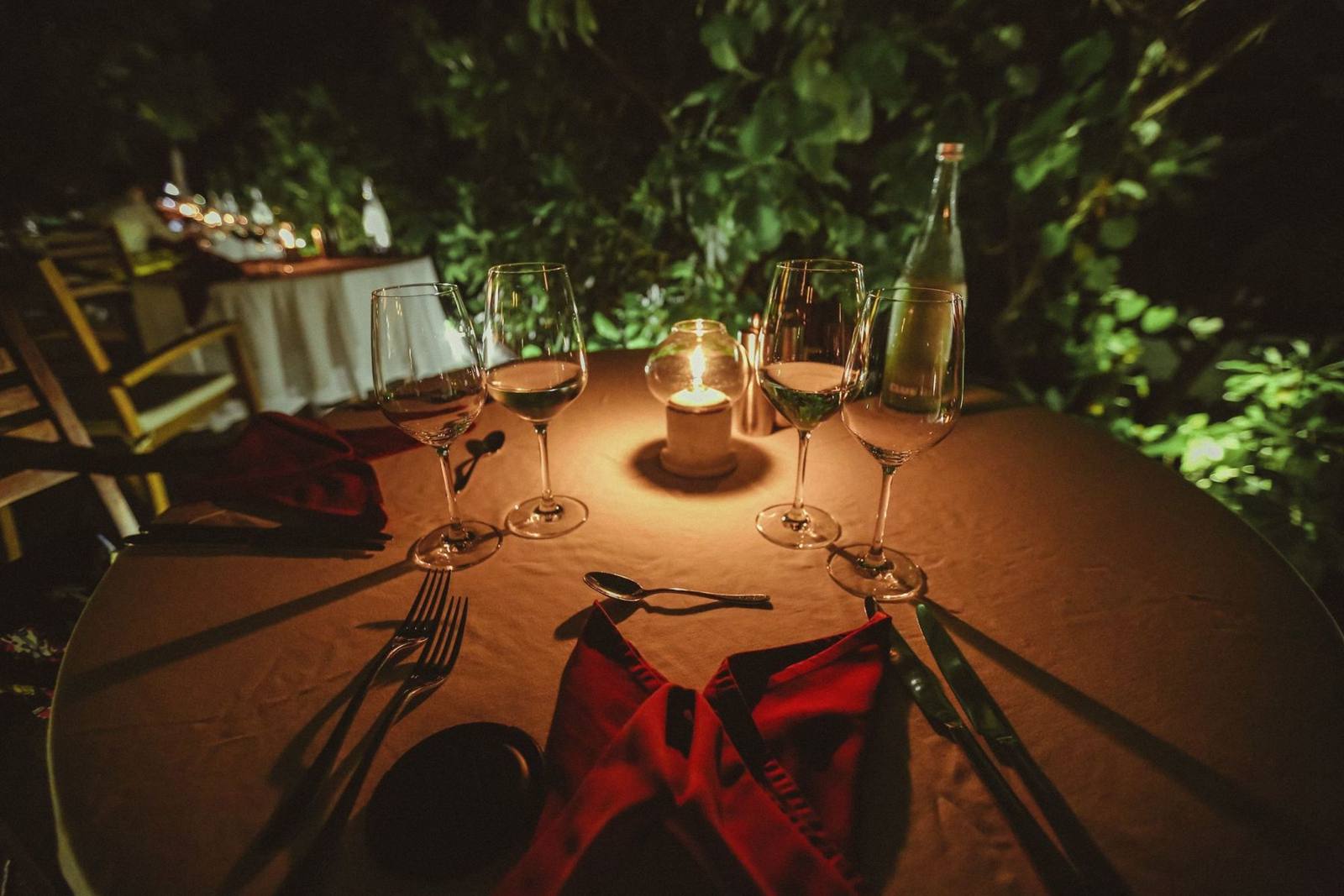 A candlelit table for two in a garden at night