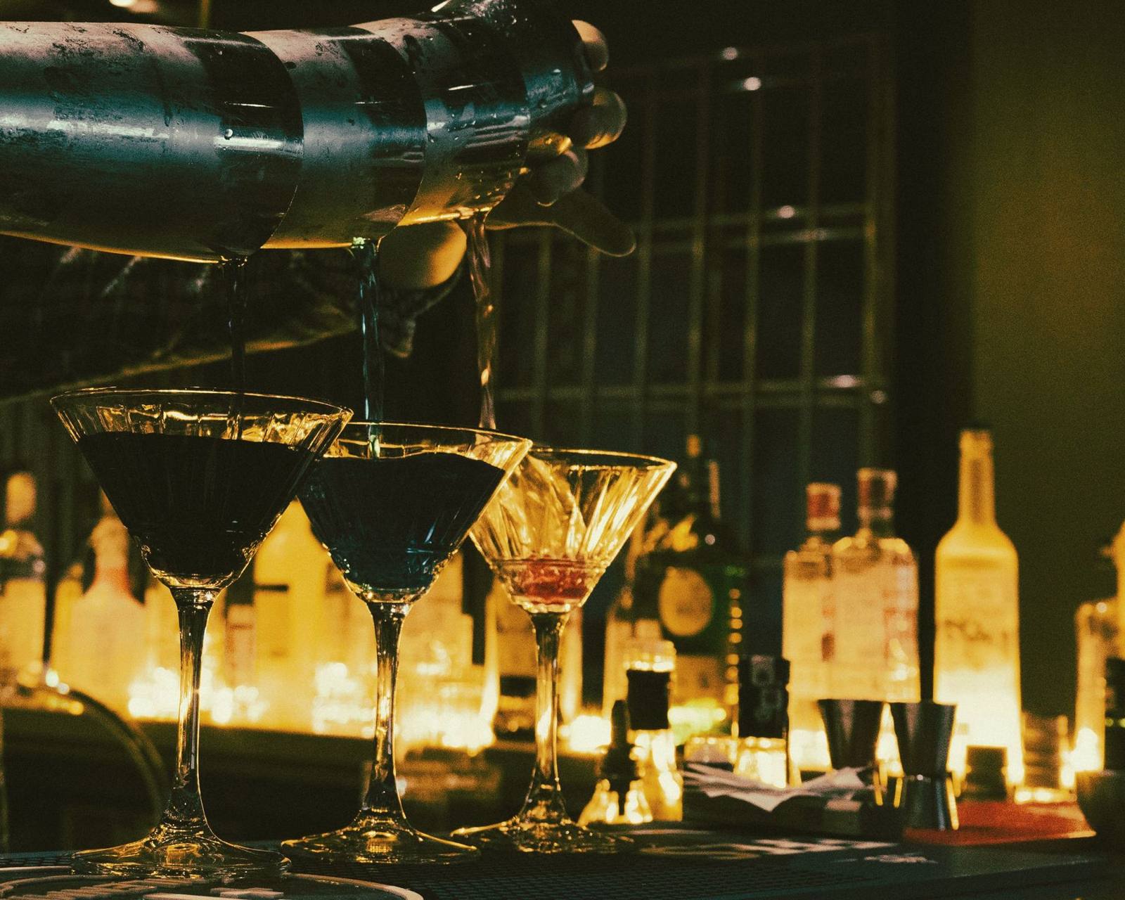 Cocktails being poured at a candlelit bar