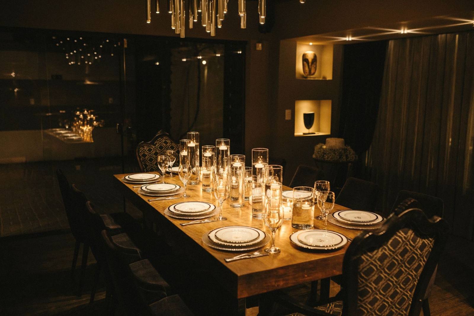 A long dinner table set with candles in a low-lit private dining room